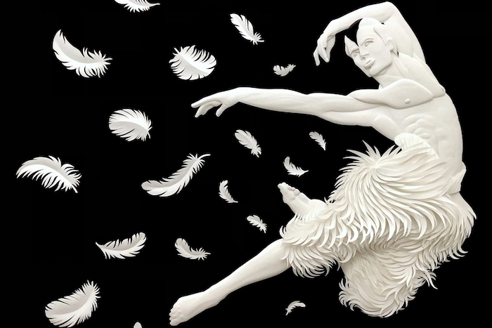 A paper-cut sculpture of a male ballet dancer with feathers floating in mid air behind him, from Matthew Bourne's production of the ballet Swan Lake.