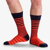 A close-up image of a man's legs wearing striped black and orange dress socks.